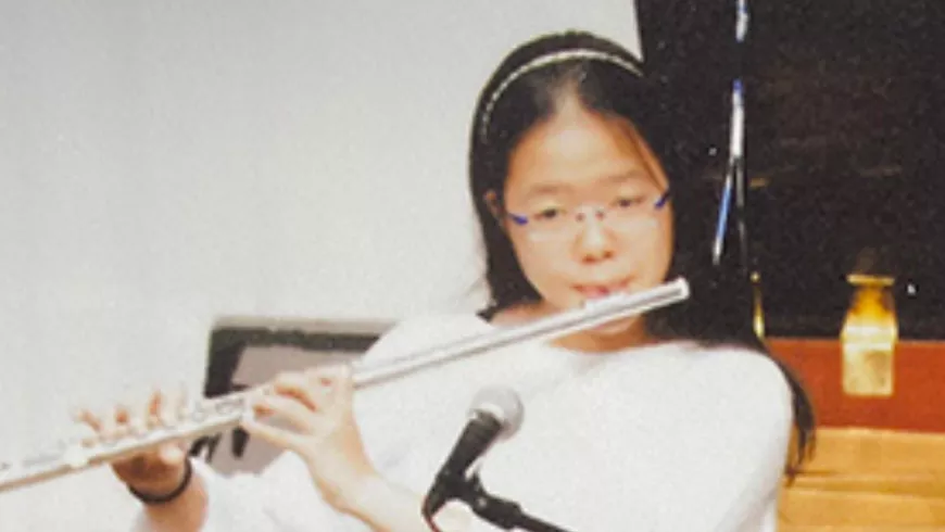 Japanese woman with long dark hair playing a wind instrument during what appears to be a concert or recital event